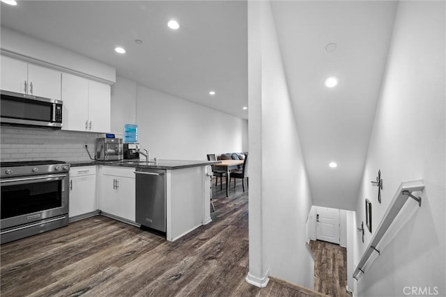 kitchen featuring stainless steel appliances, decorative backsplash, white cabinets, and kitchen peninsula