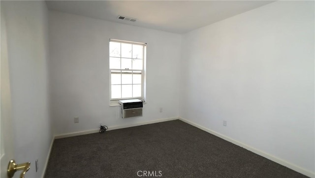 empty room featuring a wall mounted air conditioner and dark carpet