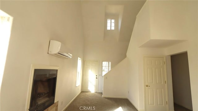 interior space featuring a high ceiling, plenty of natural light, carpet flooring, and a wall unit AC