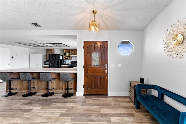 foyer with a textured ceiling and light hardwood / wood-style flooring