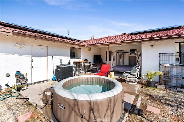 rear view of house featuring a hot tub, central AC, and solar panels