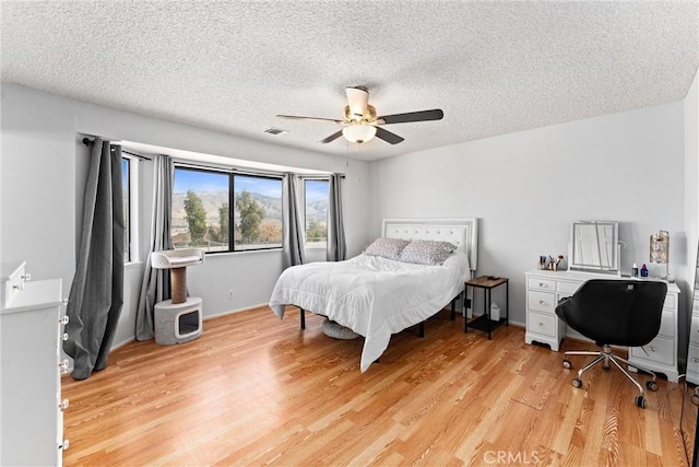 bedroom featuring light wood-type flooring, a textured ceiling, and ceiling fan