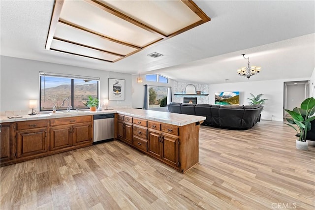 kitchen featuring stainless steel dishwasher, kitchen peninsula, sink, and light hardwood / wood-style flooring