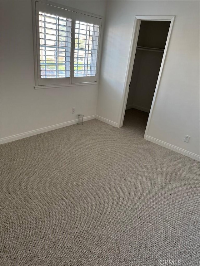 unfurnished bedroom featuring a spacious closet, carpet floors, and a closet