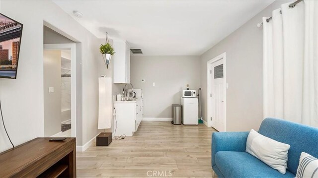 sitting room featuring sink and light wood-type flooring