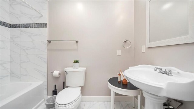 full bathroom featuring tiled shower / bath combo, sink, and toilet