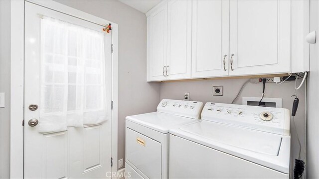 clothes washing area with cabinets and washer and clothes dryer