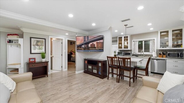 living room featuring crown molding, sink, and light hardwood / wood-style flooring