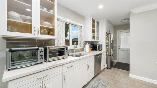 kitchen featuring tasteful backsplash, white cabinetry, appliances with stainless steel finishes, and sink