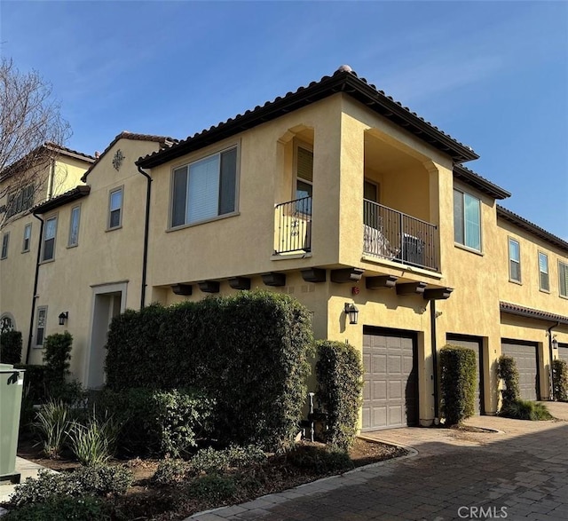 mediterranean / spanish-style home featuring a garage and a balcony