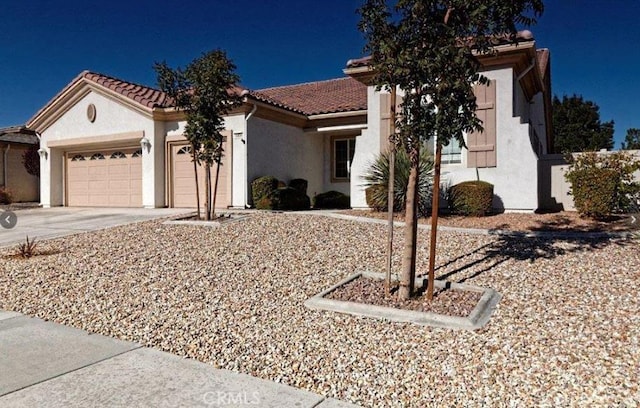 mediterranean / spanish-style home featuring concrete driveway, a tile roof, an attached garage, and stucco siding