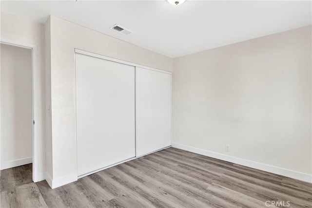 unfurnished bedroom with light hardwood / wood-style floors and a closet