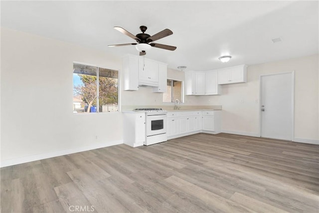 kitchen with white cabinetry, white gas range, light hardwood / wood-style flooring, and sink