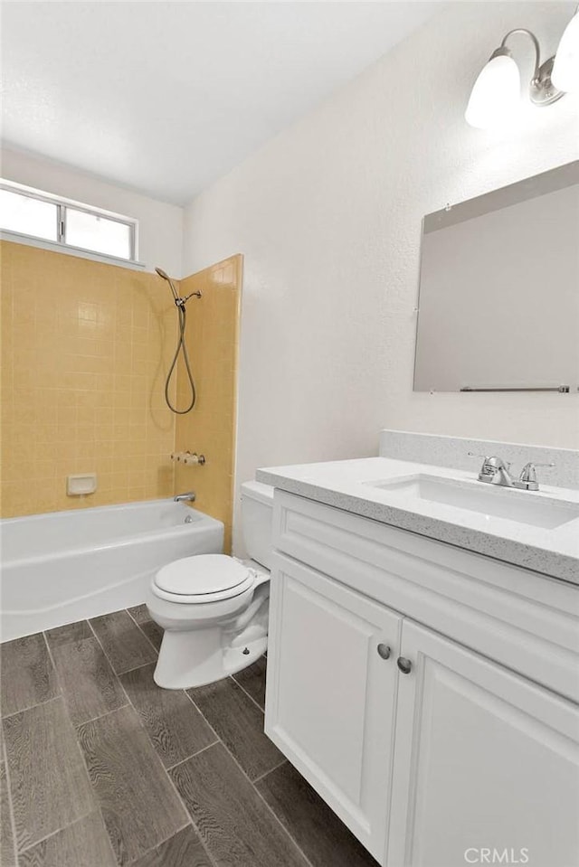 full bathroom with tiled shower / bath, vanity, and toilet