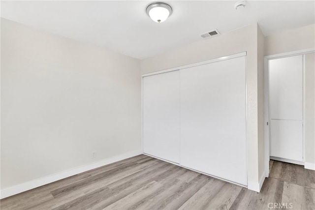 unfurnished bedroom with light hardwood / wood-style floors and a closet