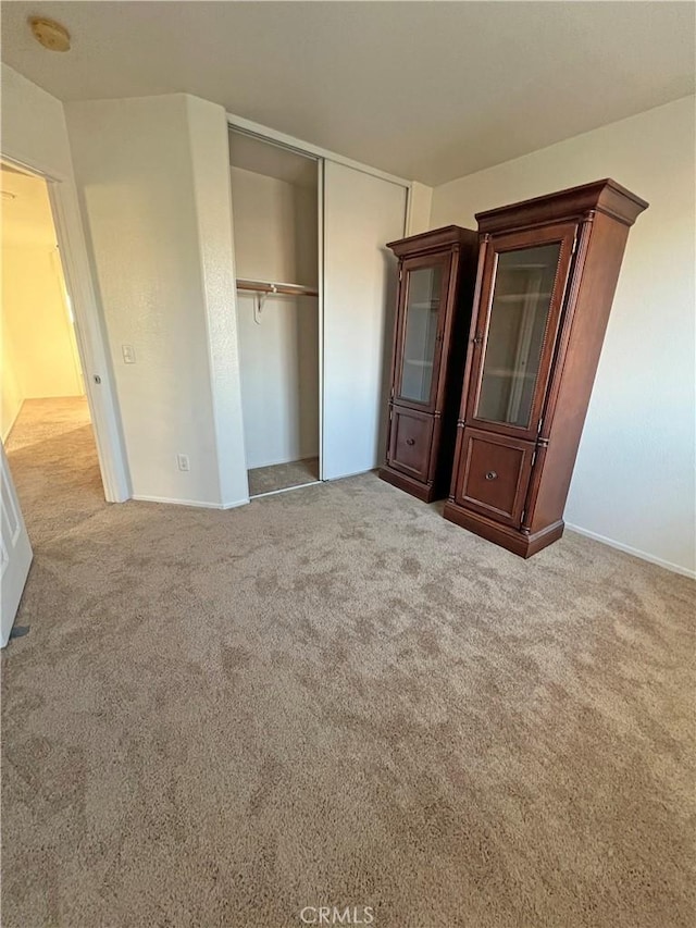 unfurnished bedroom featuring light carpet and a closet