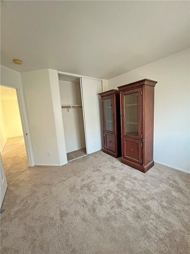 unfurnished bedroom with light colored carpet and a closet