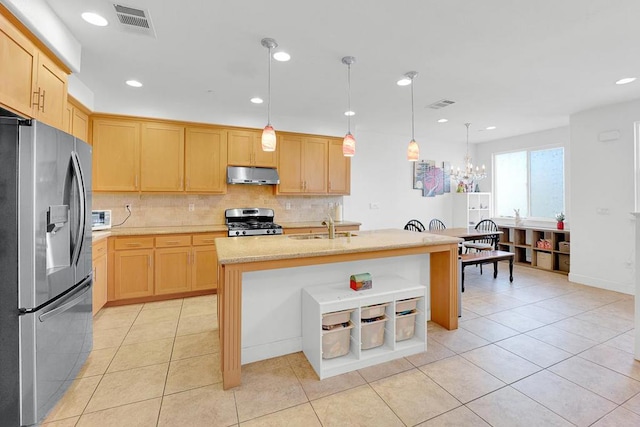 kitchen with light brown cabinetry, decorative light fixtures, sink, stainless steel appliances, and a center island with sink