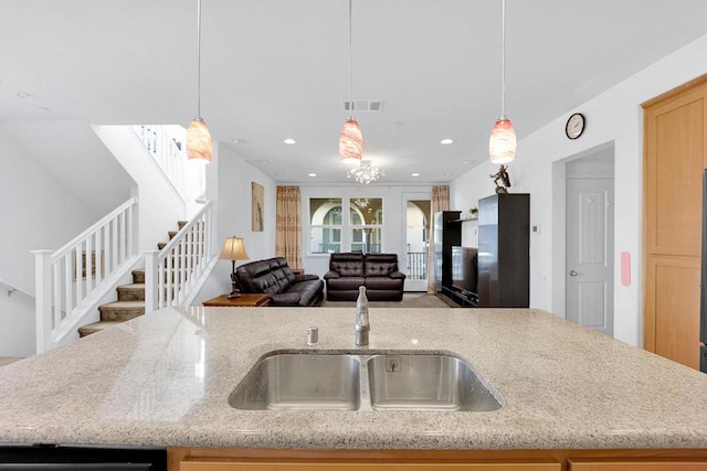 kitchen with sink, pendant lighting, and light stone counters