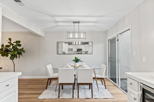 dining space with beverage cooler and light hardwood / wood-style floors