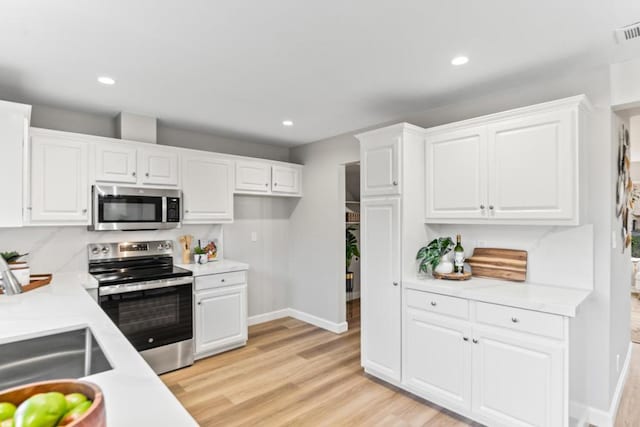 kitchen featuring white cabinetry, stainless steel appliances, and light hardwood / wood-style floors