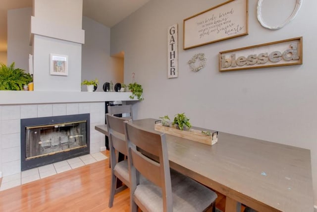 dining space with a tiled fireplace and hardwood / wood-style floors