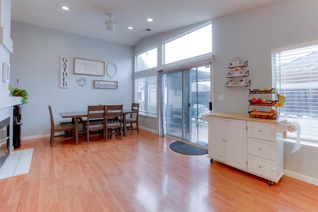 dining room with a wealth of natural light, a tile fireplace, and light wood-type flooring