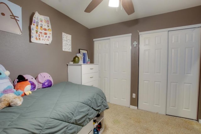 bedroom with carpet floors, two closets, and ceiling fan