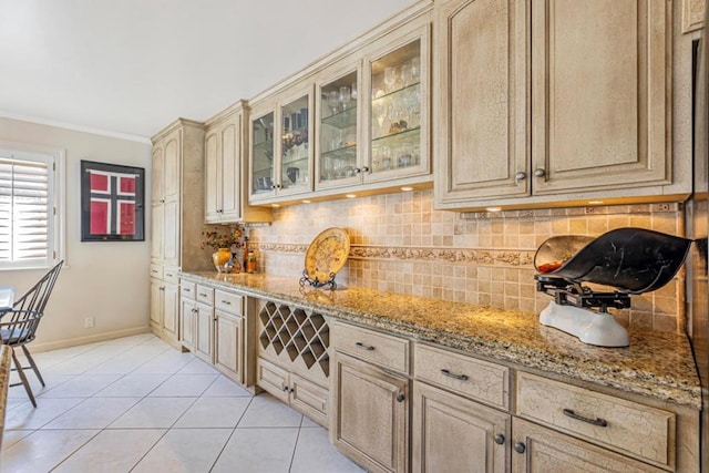 kitchen with light brown cabinets, light tile patterned floors, ornamental molding, light stone countertops, and decorative backsplash