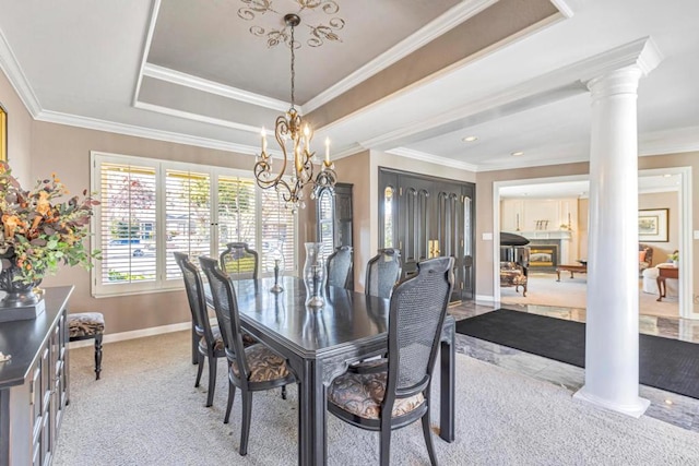 dining space featuring decorative columns, a notable chandelier, a tray ceiling, ornamental molding, and light colored carpet