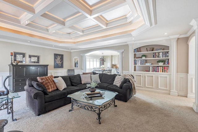 living room featuring built in features, decorative columns, ornamental molding, coffered ceiling, and light colored carpet