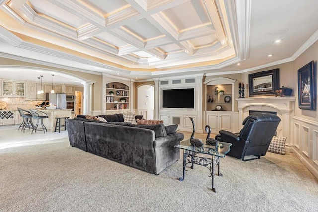 carpeted living room featuring decorative columns, ornamental molding, and built in shelves