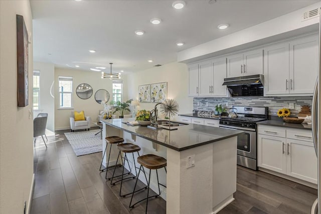 kitchen with stainless steel gas range oven, sink, a center island with sink, and white cabinets