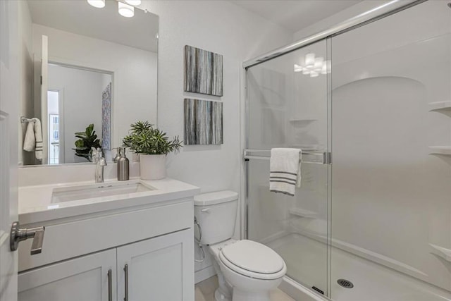 bathroom featuring vanity, toilet, and a shower with door