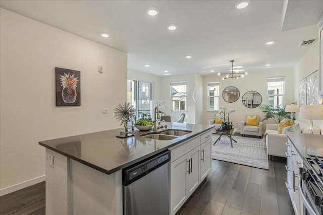 kitchen with appliances with stainless steel finishes, an island with sink, sink, white cabinets, and dark wood-type flooring