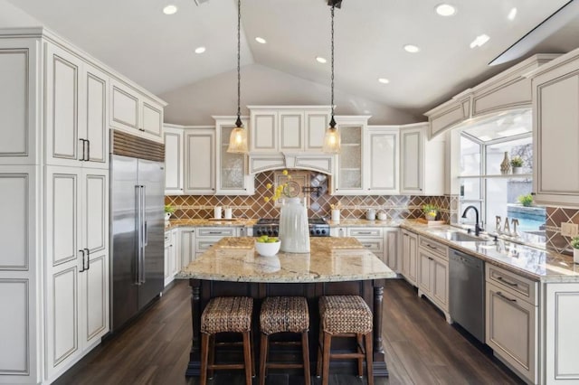 kitchen with a breakfast bar, appliances with stainless steel finishes, backsplash, a center island, and dark hardwood / wood-style flooring