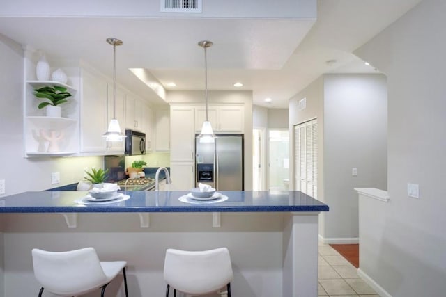 kitchen with a kitchen bar, white cabinetry, stainless steel fridge, kitchen peninsula, and pendant lighting