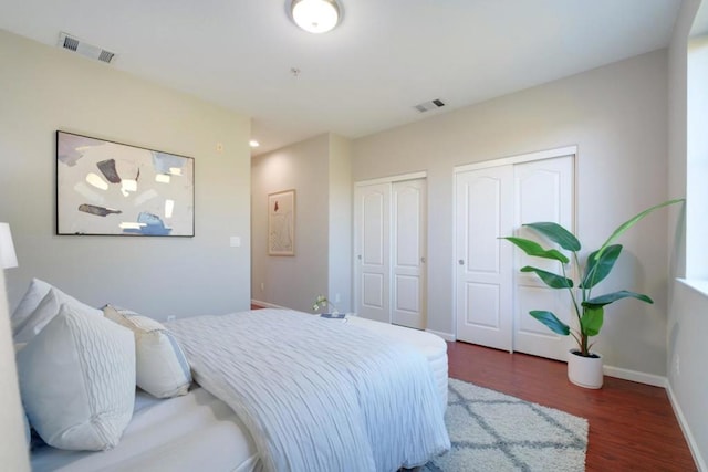 bedroom with dark wood-type flooring and multiple closets