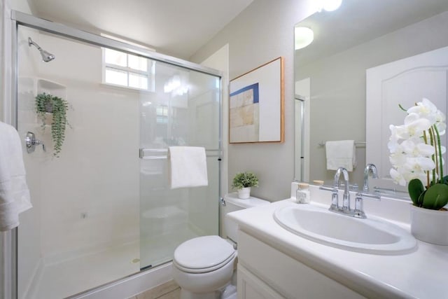 bathroom featuring vanity, a shower with shower door, and toilet