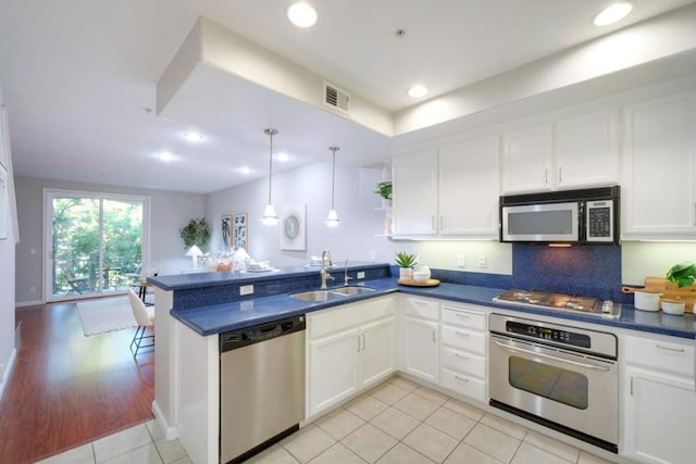 kitchen featuring stainless steel appliances, white cabinetry, sink, and kitchen peninsula