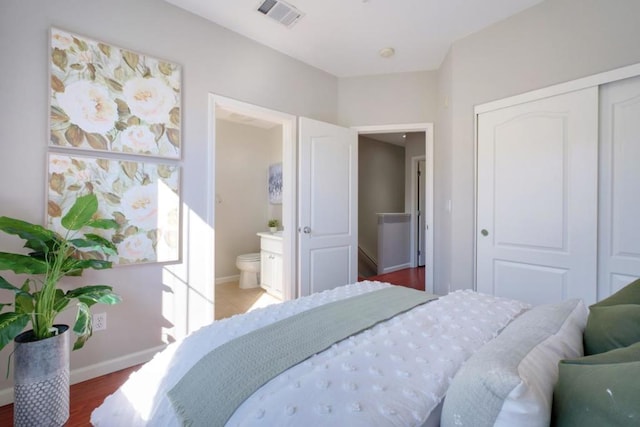 bedroom with hardwood / wood-style flooring, ensuite bath, and a closet