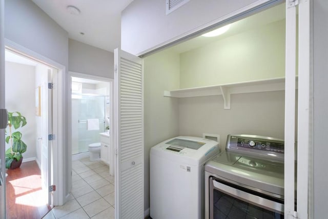 laundry area featuring washing machine and dryer and light tile patterned floors