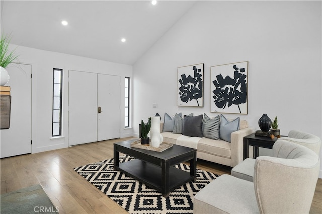 living room with high vaulted ceiling and light wood-type flooring