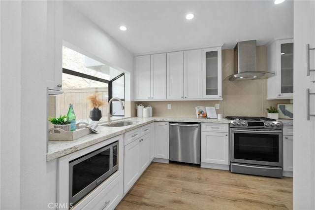 kitchen with white cabinetry, appliances with stainless steel finishes, sink, and wall chimney exhaust hood