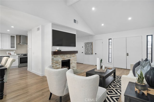 living room with a fireplace, light hardwood / wood-style flooring, and vaulted ceiling with beams