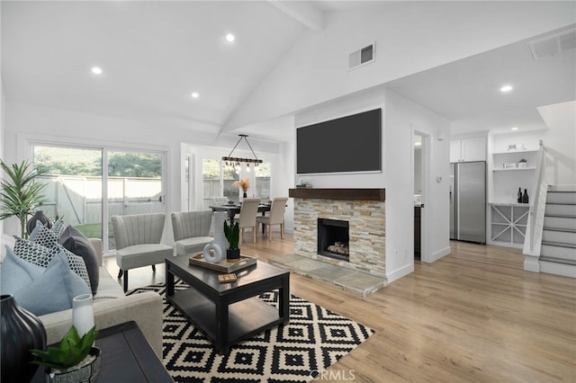 living room with high vaulted ceiling, beam ceiling, a fireplace, and light hardwood / wood-style floors