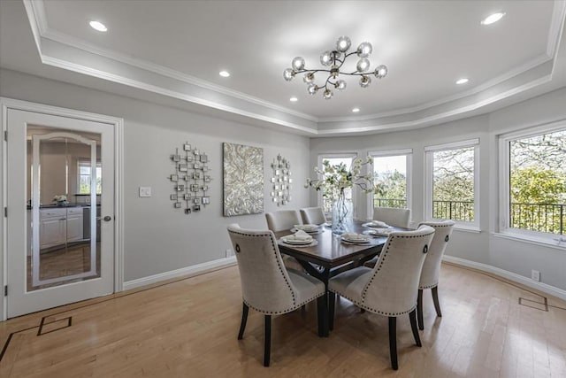 dining room with crown molding, an inviting chandelier, light hardwood / wood-style floors, and a tray ceiling