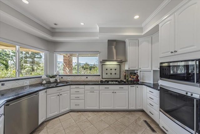 kitchen with white cabinets, appliances with stainless steel finishes, sink, and wall chimney range hood