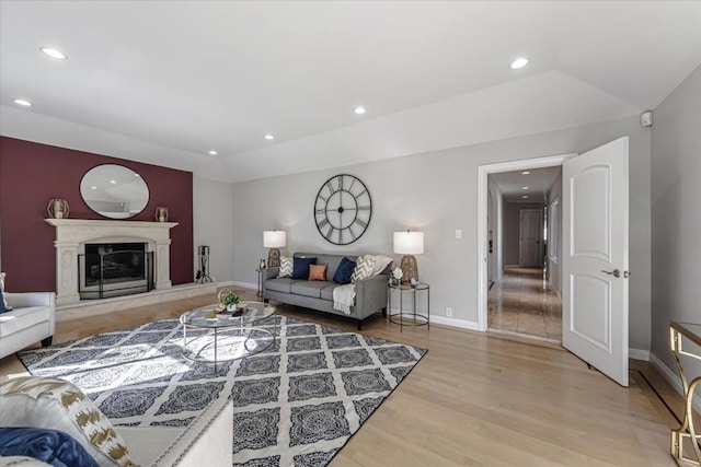 living room with vaulted ceiling, a high end fireplace, and light wood-type flooring