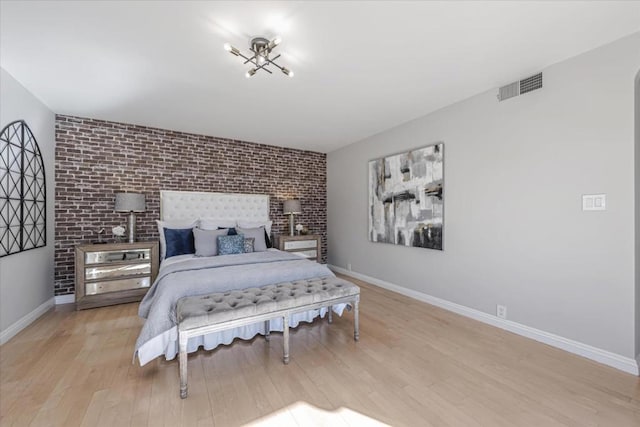 bedroom featuring brick wall and light wood-type flooring